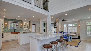 Una cocina amplia con una isla grande, taburetes de bar y un comedor con mesa y sillas.