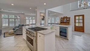 Una cocina amplia con isla central, horno empotrado y un refrigerador para vinos.