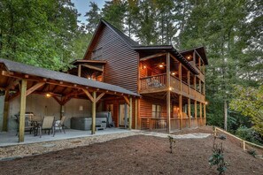 A two-story log cabin with a covered patio and a deck.