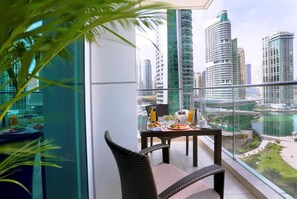 A balcony with a dining table set for breakfast, overlooking a cityscape with modern buildings and a body of water. - Luxurious Hotel Apartment with incredible views (Dubai)