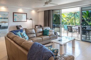 Una sala moderna con un sofá de cuero, una mesa de centro y vistas a un espacio exterior tropical.