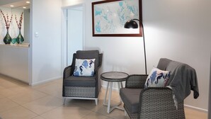 Una sala de estar moderna con dos sillones de mimbre, una mesita redonda y un mapa enmarcado en la pared.