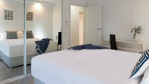 Un dormitorio con cama, mesita de noche, espejo y ventilador de techo.