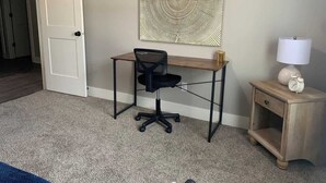 A room with a desk, chair, and a small bedside table with a lamp. - Bettendorf Condo: Fireplace, King Bed & Family Fun! (Bettendorf)