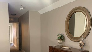 A hallway with a wooden bench, a dresser with a mirror, and a plant on the dresser. - Bettendorf Condo: Fireplace, King Bed & Family Fun! (Bettendorf)