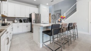 A modern kitchen with white cabinets, stainless steel appliances, and a central island with bar stools.