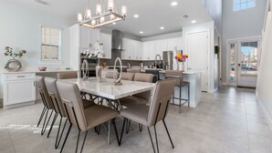 A modern kitchen with a central island, white cabinetry, and a chandelier.