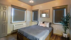 Ein Schlafzimmer mit Bett, Heizkörper, Tür und Fenster.