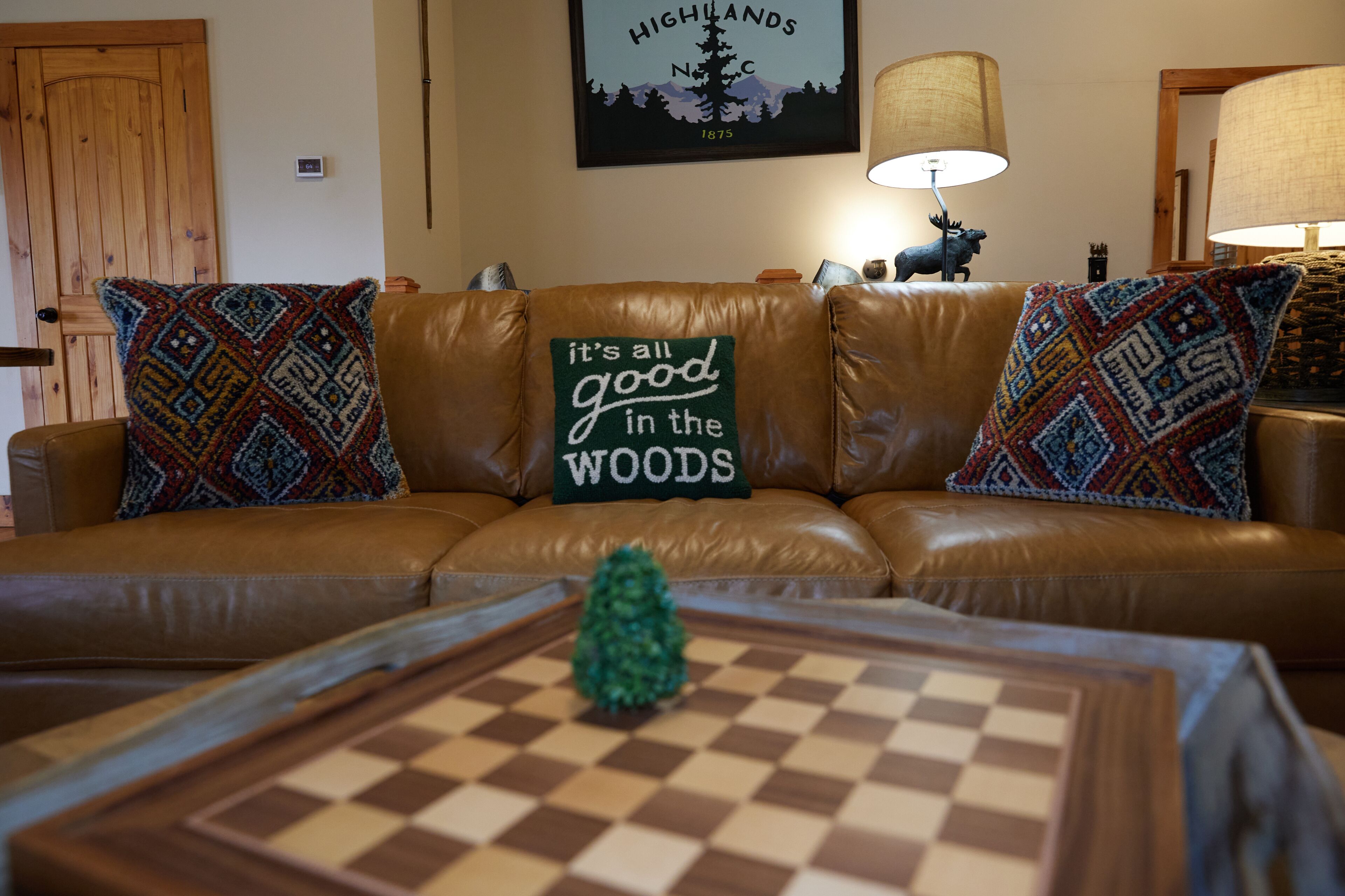 A brown leather sofa with patterned throw pillows and a cushion with text.