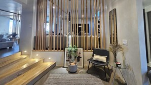 A modern interior with a wooden slatted ceiling, a staircase leading to a living area, a black leather chair, and a potted plant. - Modern Maison in the middle of Santa Fe (Santa Fe)