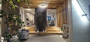 A modern interior with a staircase leading to a living area, a large pillar, and a hanging light fixture.