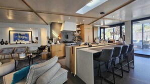 A modern kitchen with a central island, a dining area with bar stools, and a living room with a sofa and chairs. - Modern Maison in the middle of Santa Fe (Santa Fe)