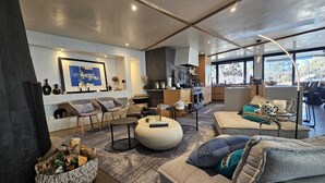 A modern living room with a sofa, chairs, a coffee table, and a fireplace. There is a kitchen area with a stove and cabinets. - Modern Maison in the middle of Santa Fe (Santa Fe)