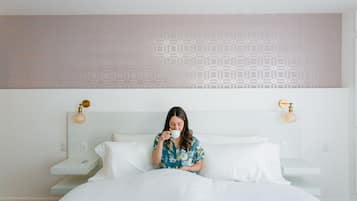 Una habitación de hotel con cama, mesita de noche y pared con diseño geométrico.