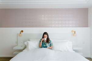 Una habitación de hotel con cama, mesita de noche y pared con diseño geométrico.