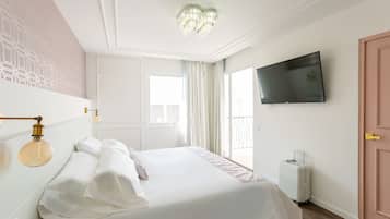 Una habitación de hotel con una cama grande, un televisor montado en la pared y una ventana con cortinas.