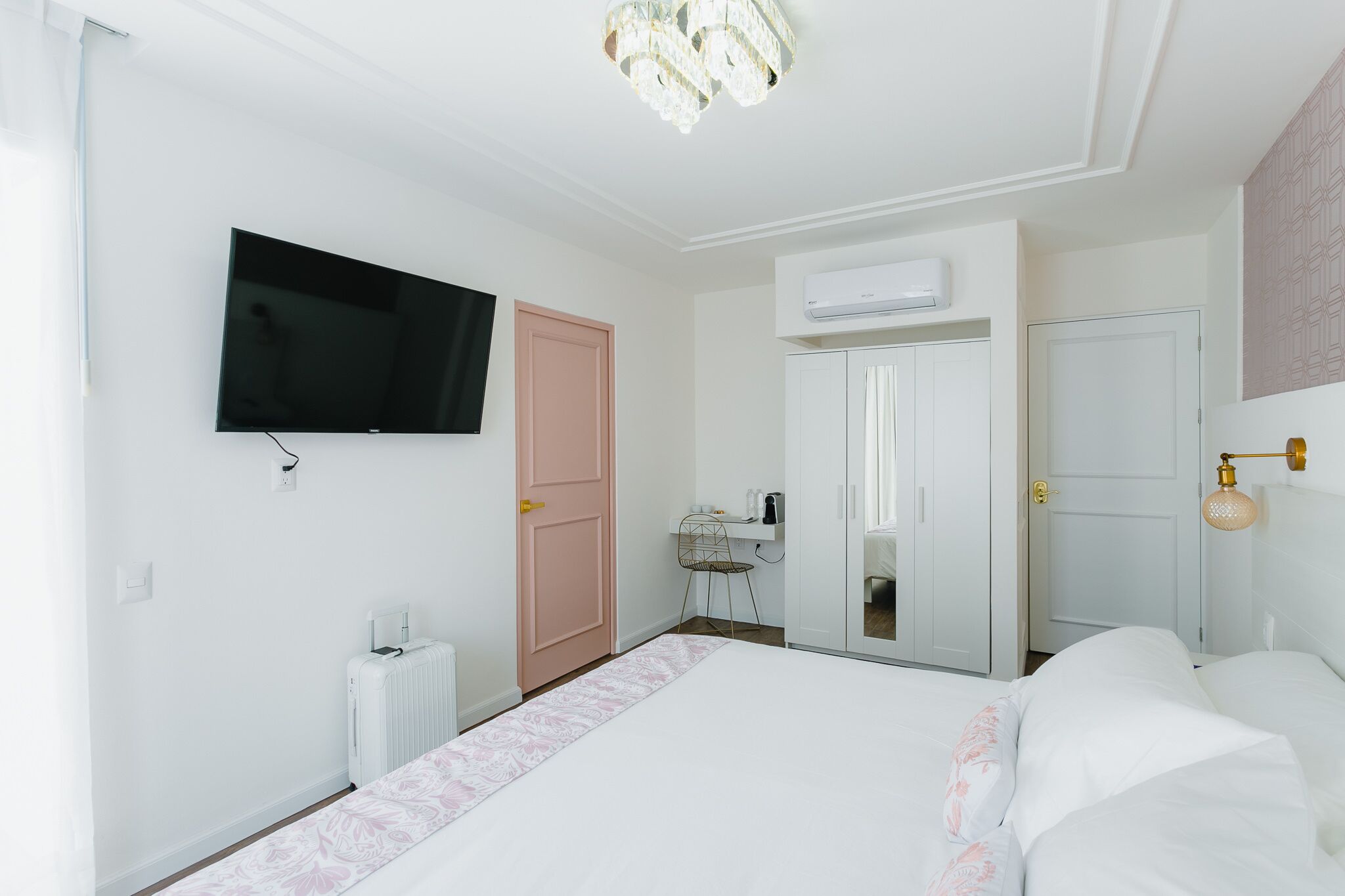 A bedroom with a bed, a television, a radiator, a wardrobe, and an air conditioning unit.