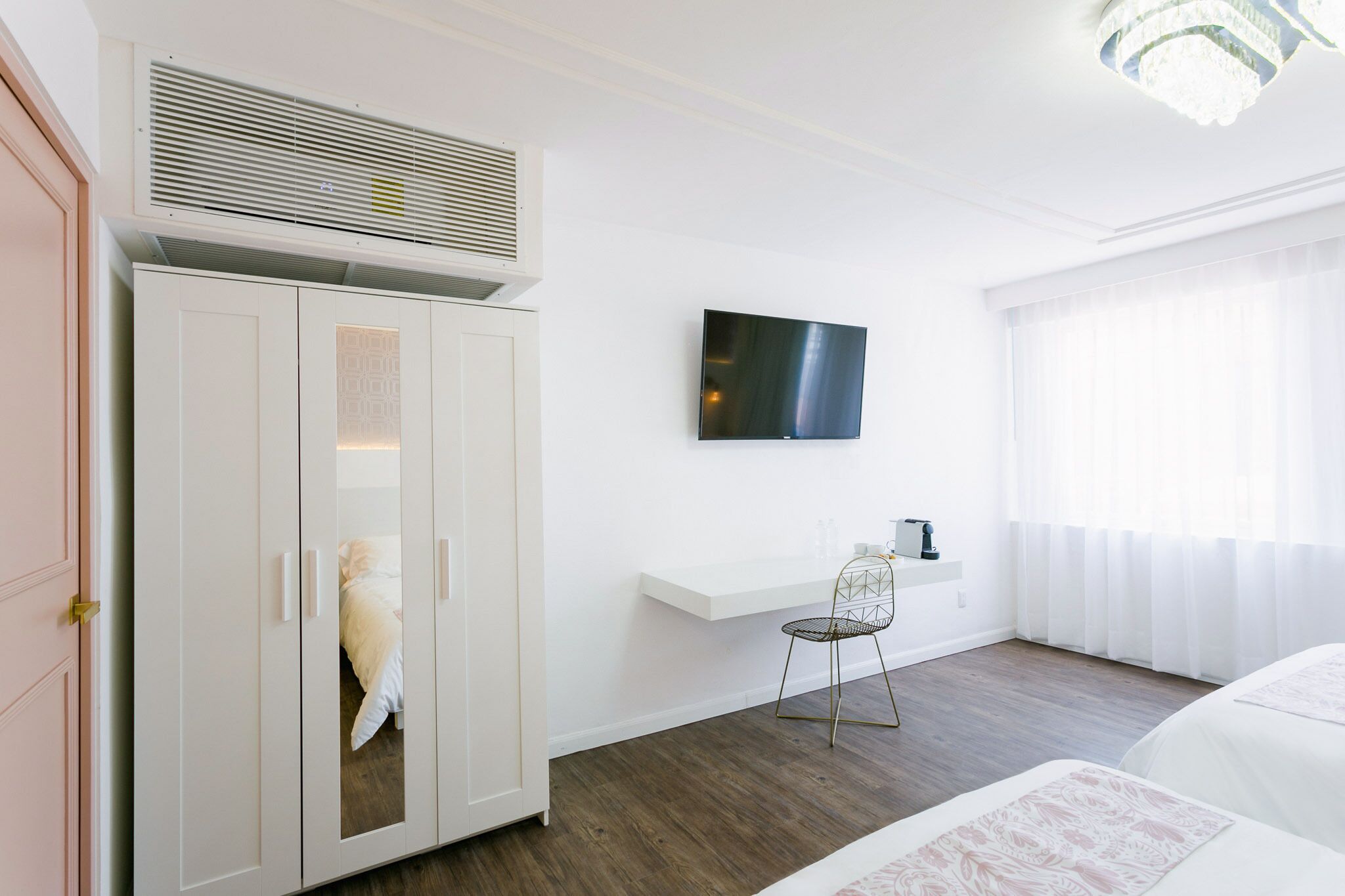 A hotel room with a bed, a wardrobe, a TV, a desk, and a chair.