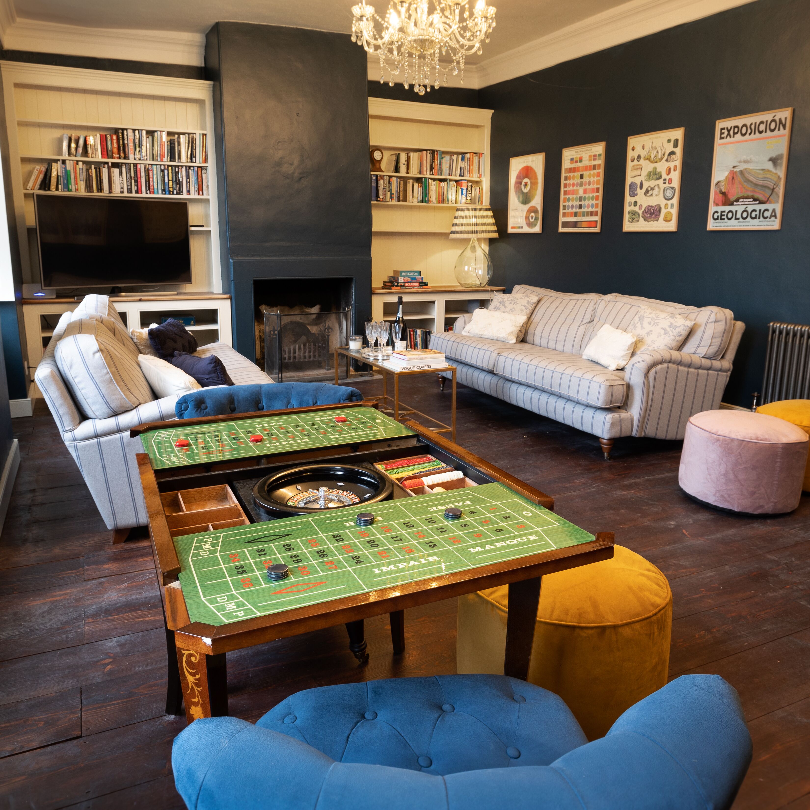 A living room with a pool table, sofas, a fireplace, bookshelves, and a television.