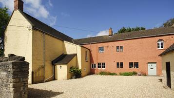 A two-story building with a gravel driveway and a stone wall.