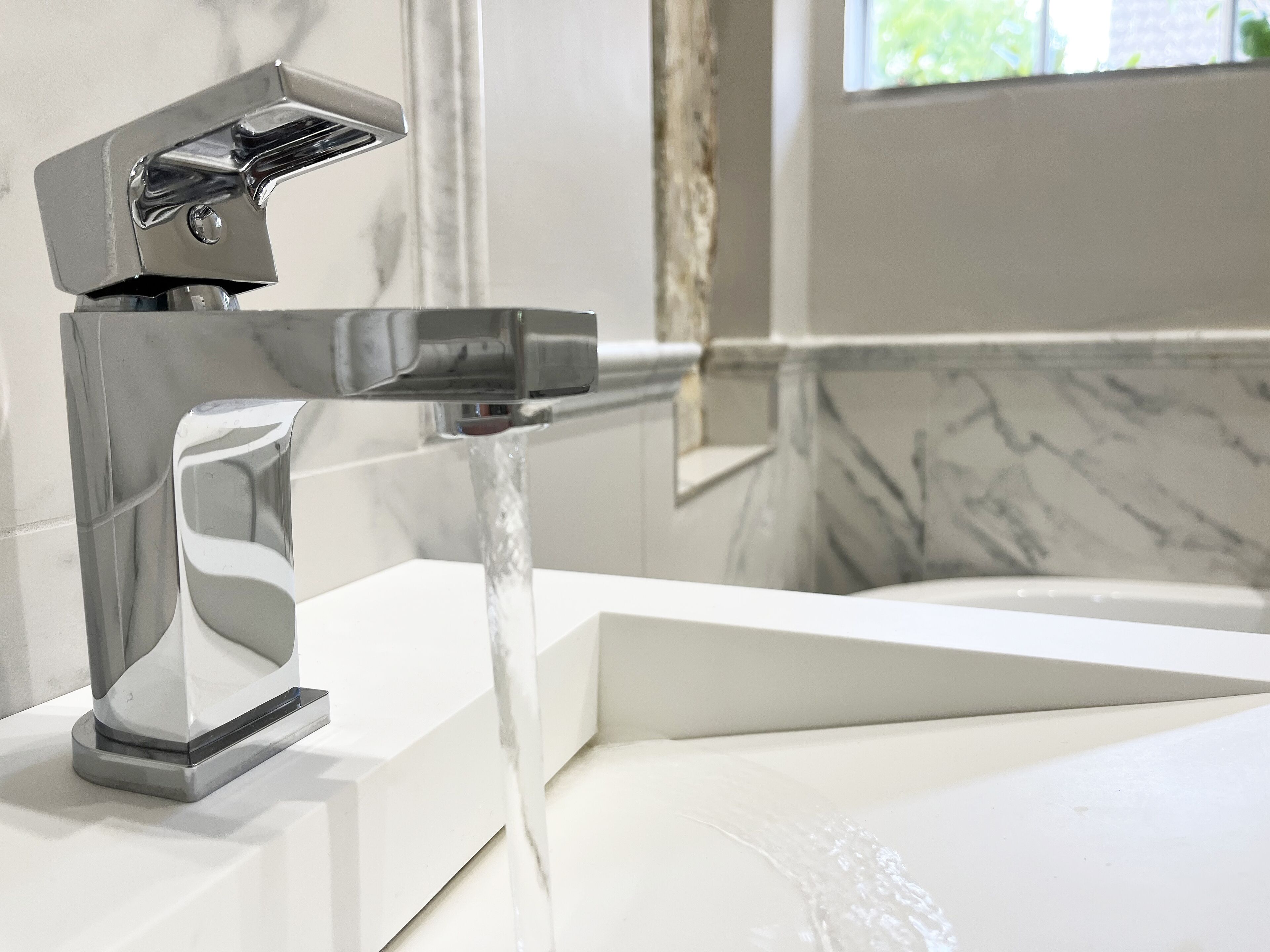 A modern bathroom with a chrome faucet and a white sink.