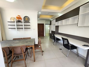 A modern dining area with a marble table, wooden chairs, and a white wall with shelves. - Red Rose Apartment, Unit # 401 (Kigali)