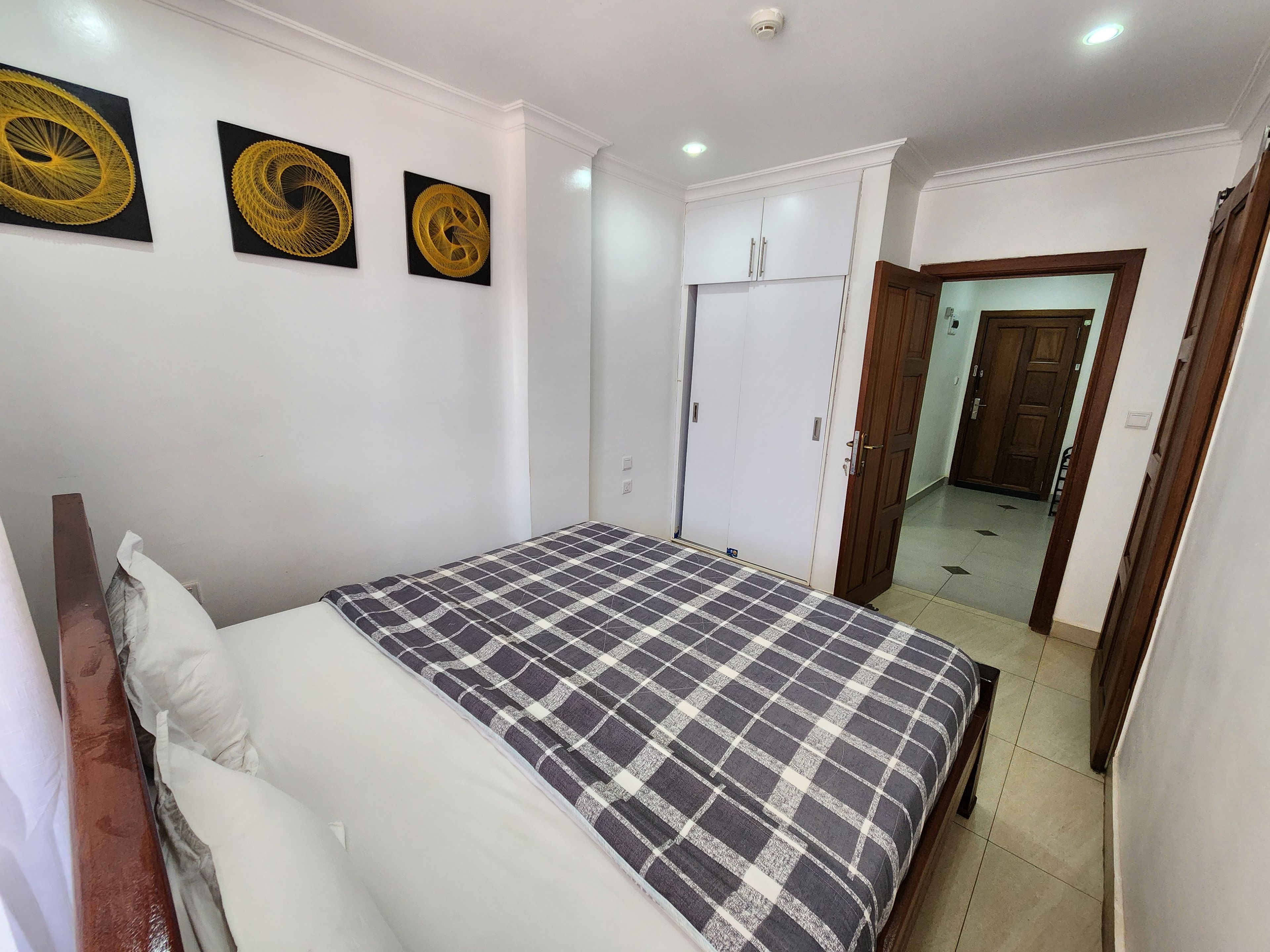 Une chambre à coucher comprenant un lit, une armoire et trois œuvres d’art accrochées au mur.