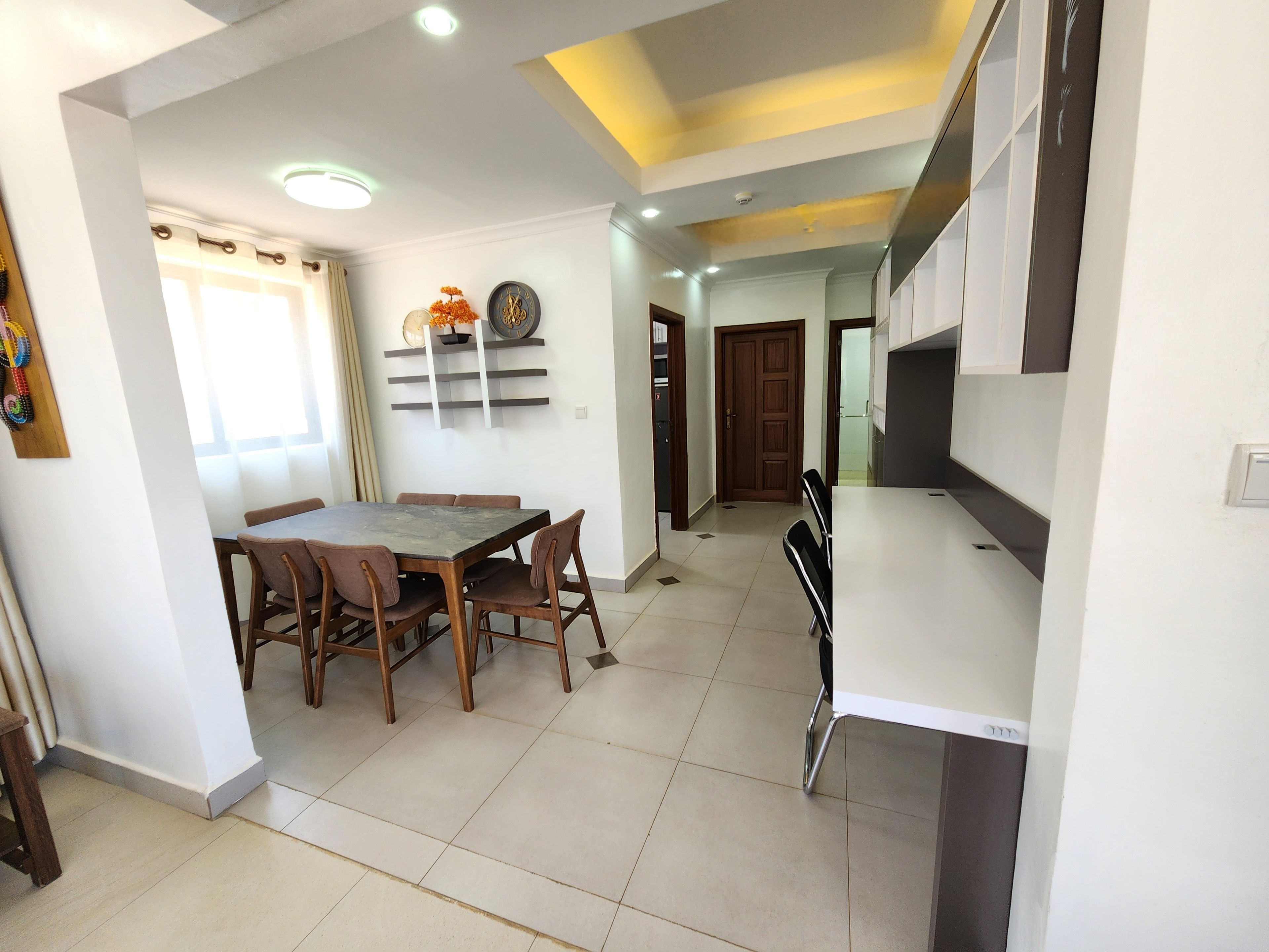 A dining area with a table and chairs, a kitchen with a countertop, and a door leading to another room.
