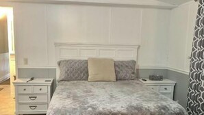 A bedroom with a bed, bedside tables, a nightstand, and a patterned rug.