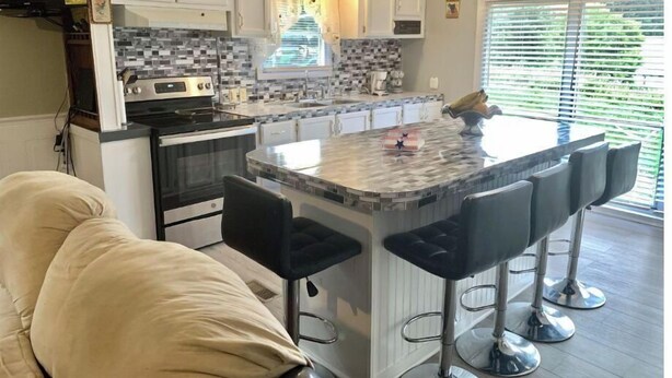 A kitchen with a central island, bar stools, and a dining area with a couch.
