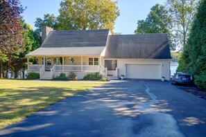 Ein zweistöckiges Haus mit einer Veranda, einer Garage und einer Auffahrt zur Garage.