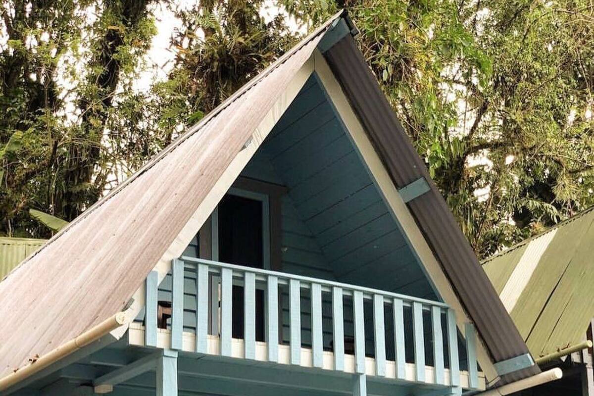 A two-story house with a balcony, a porch, and a wooden roof.