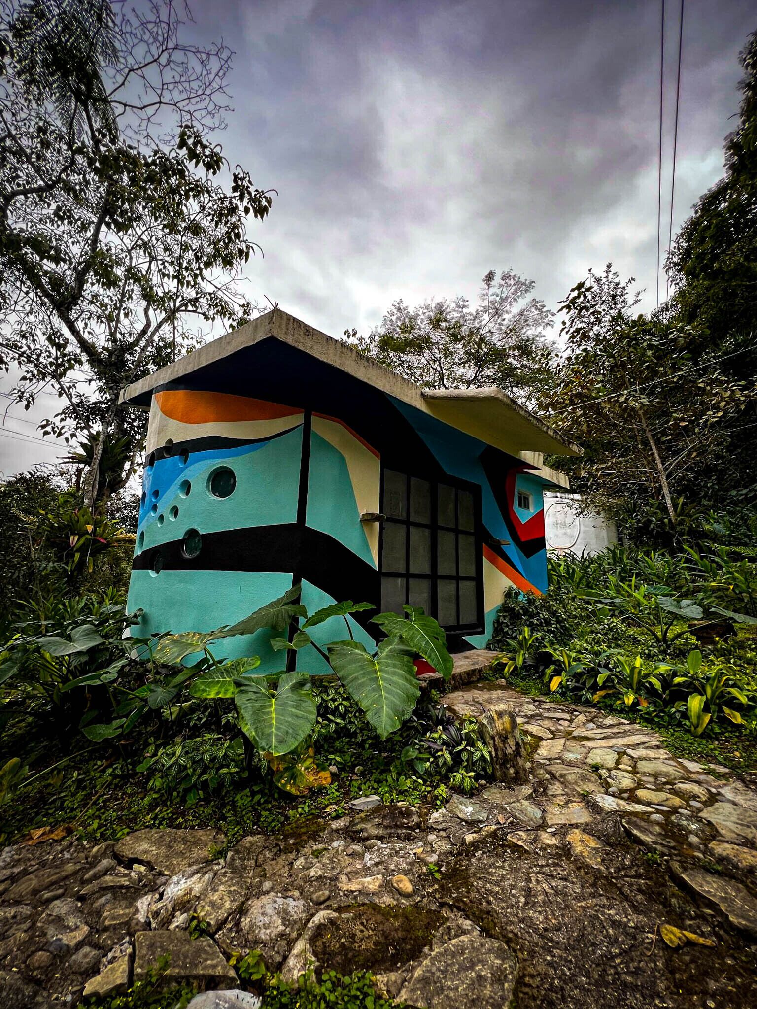 A colorful, uniquely designed building surrounded by lush greenery.