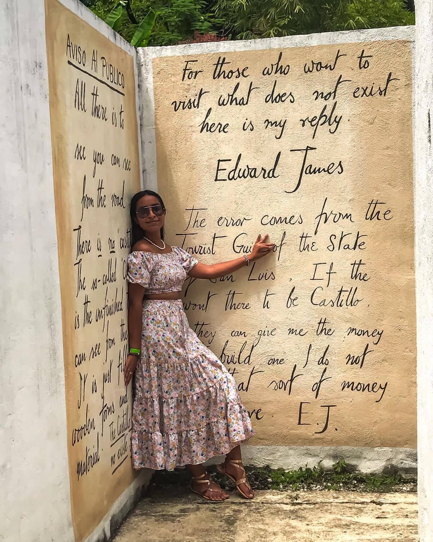 Una persona de pie junto a una pared con texto escrito a mano.