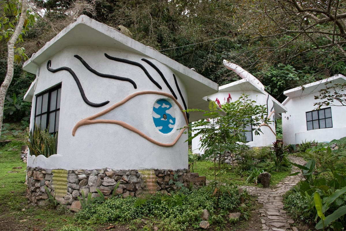 A white building with a unique design, including a blue and brown circular window and a stone base.