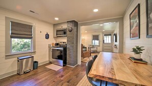 Une cuisine moderne avec un mur d’accent en pierre, un plancher en bois et un coin repas doté d’une grande table et de chaises.