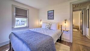Une chambre avec un grand lit, une fenêtre avec des stores, une décoration murale représentant un vélo et un tableau encadré au-dessus du lit.