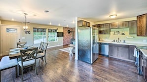A modern kitchen with a central island, stainless steel appliances, and a view to the outside.