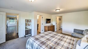 A bedroom with a large bed, a dresser, a television, and a bookshelf.