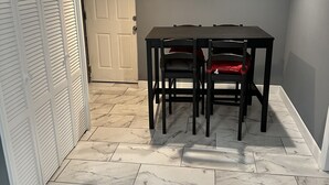 A dining area with a table and chairs, a sliding door, and a window with blinds.