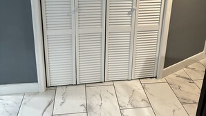 A room with a closed white closet, grey walls, and marble tiled flooring.