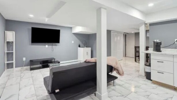 A modern hotel room with a bed, a flat-screen TV, a small kitchenette, and a bathroom.