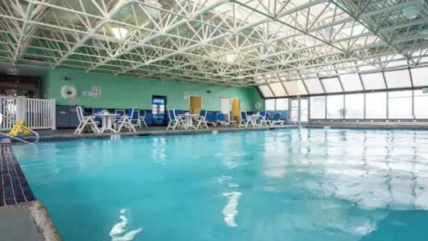 Une piscine intérieure dotée d’un haut plafond et de murs en verre transparent.