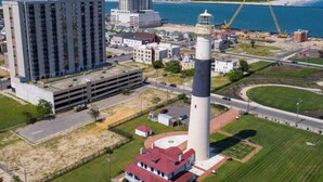 Une zone côtière comprenant un phare, un immeuble à plusieurs étages et un bâtiment plus petit avec un toit rouge.