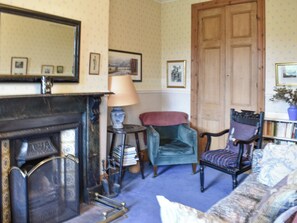 A traditional room with a fireplace, a blue armchair, a wooden door, and a bookshelf. - 3 bedroom accommodation in Howtown on Ullswater (Howtown on Ullswater)