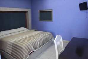 A room with a bed, a small table, a chair, a window, and a wall-mounted TV. - Hn Hotel (Durango)