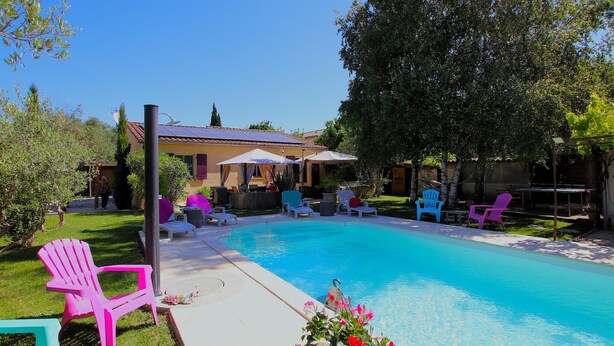 A backyard with a swimming pool, outdoor furniture, and a house in the background.