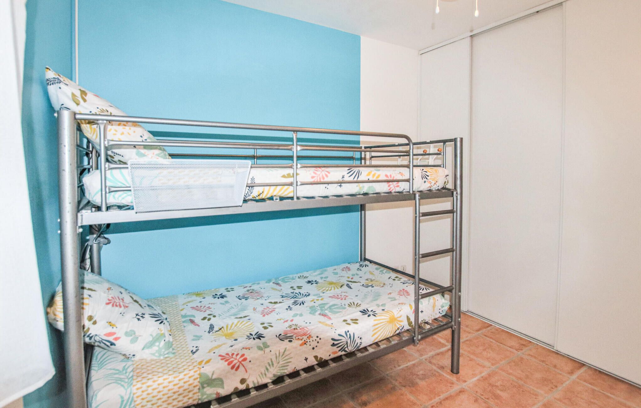 A bunk bed with floral-patterned bedding in a room with blue and white walls.