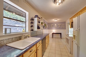 A kitchen with a large window, a sink, a dishwasher, and a refrigerator. - Secluded Vian Retreat Close to Tenkiller Lake (Vian)