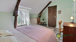 Un dormitorio con una cama grande, un escritorio de madera, una silla, un radiador y una puerta.